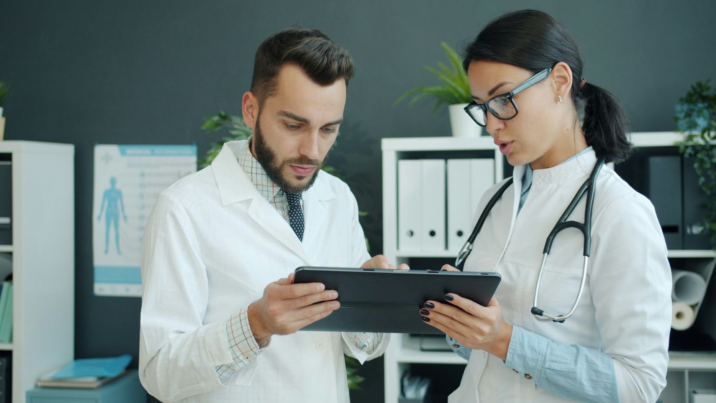 Hands typing on a laptop beside a stethoscope